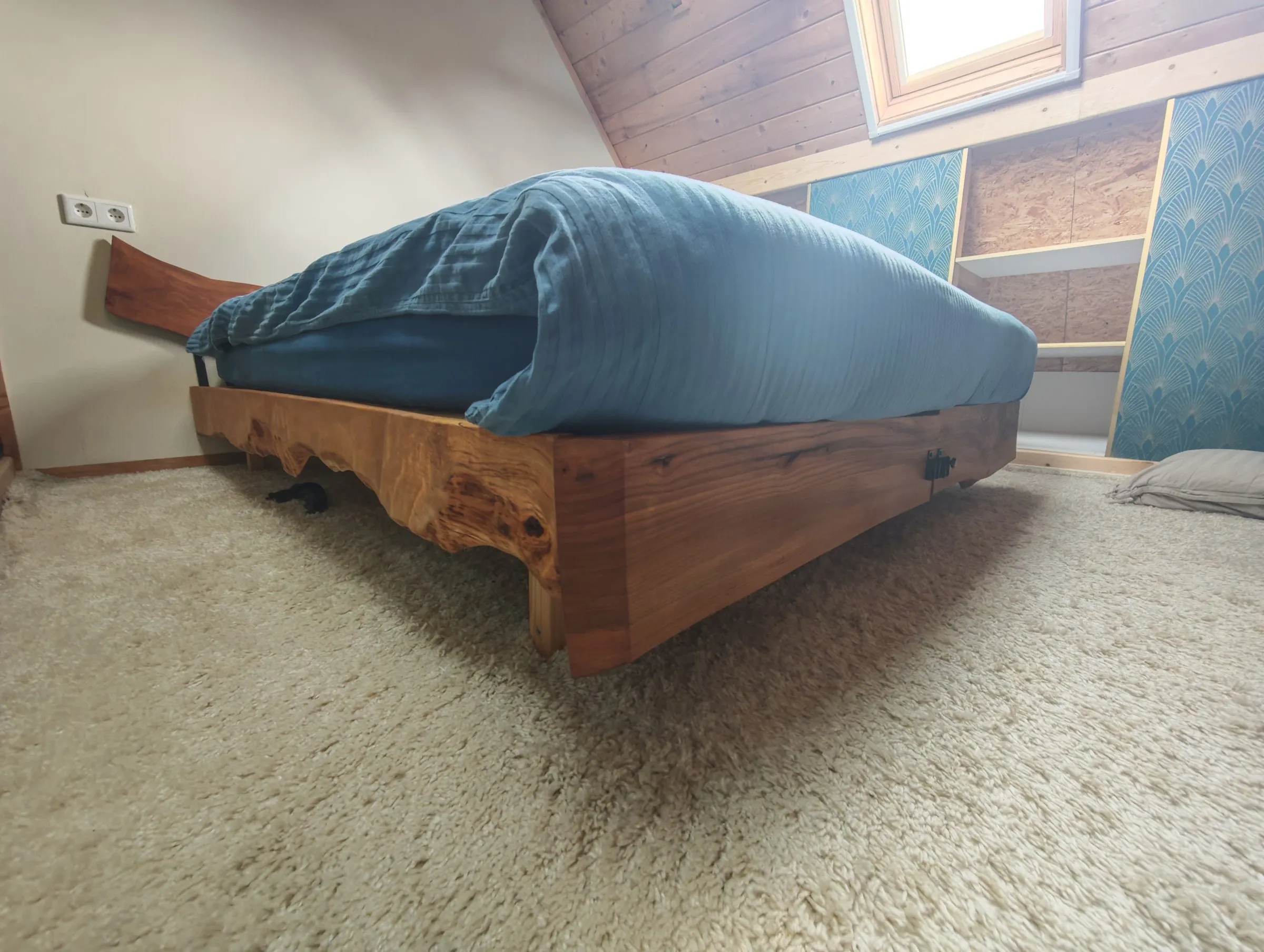Het bed van opzij, met het hoofdbord met boomrand tegen de muur